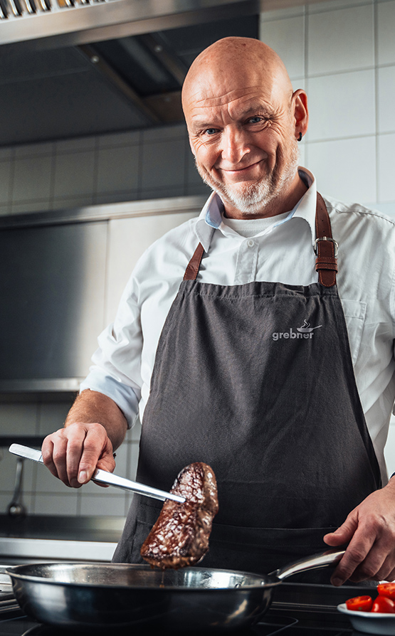 Koch beim Braten eines Steaks in einer professionellen Küche